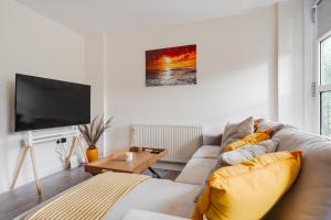 a living room with a couch and a tv at Brimmond Homes - nr to Univ, Hospitals, o2 Apollo, PLAB & 7 mins to City Centre - Stylish, Modern & Secure 2 Bed, 2 Bath Apt with Allocated Free Parking in Manchester