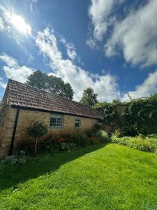 a house with a grass yard in front of it at Little Old Barn at Manor Farmhouse in West Chinnock