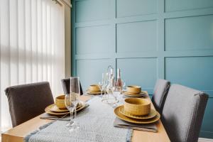 a table with chairs and plates and wine glasses at Brimmond Homes - nr to Univ, Hospitals, o2 Apollo, PLAB & 7 mins to City Centre - Stylish, Modern & Secure 2 Bed, 2 Bath Apt with Allocated Free Parking in Manchester