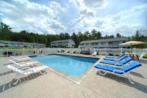a pool with two lounge chairs and an umbrella at Studio Motel of Lake George in Lake George