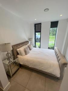 a bedroom with a bed and a lamp and windows at Stunning Luxury in Central Alderley Edge in Alderley Edge