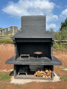 un barbecue nero con un mucchio di legna da ardere di Villa Ema a Pale