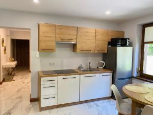 a kitchen with white cabinets and a refrigerator and a table at Mountain View Guest Rooms in Jedlina-Zdrój