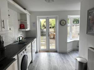 a kitchen with a clock on the wall next to a door at Chaplin House in Sileby