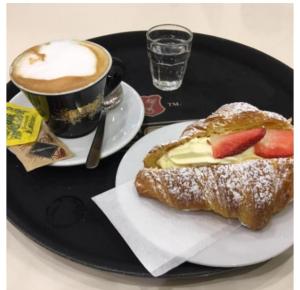 a table with a plate with a pastry and a cup of coffee at Residenza le Torri in Bologna