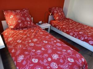 2 camas en una habitación con edredón rojo en die Senfbude - schöne, ebenerdige 2-Raum-Apartments mit Stellplatz und Terrasse, en Leipzig