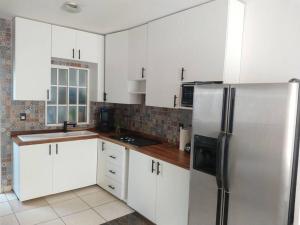 Casa Alberca Privada 5 min de Playa Nuevo Vallarta في Jarretadera: مطبخ مع دواليب بيضاء وثلاجة ستانلس ستيل