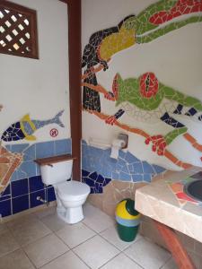 a bathroom with a toilet and a mosaic wall at Pagalù Hostel in Puerto Viejo