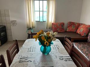 a dining room table with a vase of flowers on it at APTOS FAMILIA com AR CONDICIONADO UBATUBA Praia Pereque Acu in Ubatuba