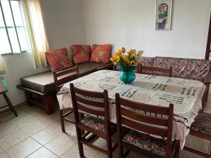 a dining room table with a vase of flowers on it at APTOS FAMILIA com AR CONDICIONADO UBATUBA Praia Pereque Acu in Ubatuba