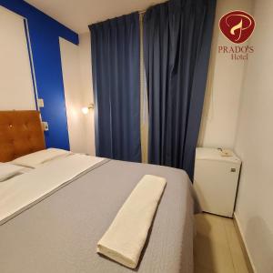 1 dormitorio con cama y cortina azul en Hotel Prados Piura - Oficial, en Piura