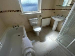 a bathroom with a tub and a toilet and a sink at Lily’s Town House in Buncrana