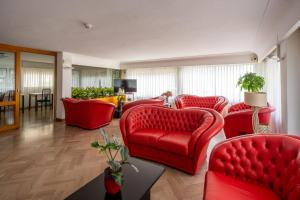 - un salon avec des canapés rouges et une table dans l'établissement Hotel Eden, à Bellaria-Igea Marina