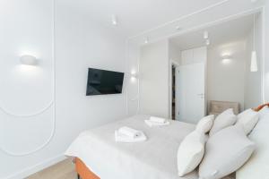a white bedroom with a bed with white pillows at Apartament z basenem Polanki Aqua D307 in Kołobrzeg +52 photos
