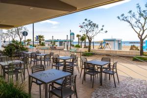 a patio with tables and chairs and the beach at Hotel Eden in Bellaria-Igea Marina