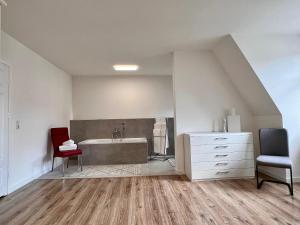 ein Badezimmer mit einer Badewanne, einem Stuhl und einer Kommode in der Unterkunft Apartment Kander in Görlitz