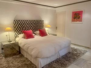 a bedroom with a large white bed with two red pillows at Villa in a palm tree plantation in Marbella