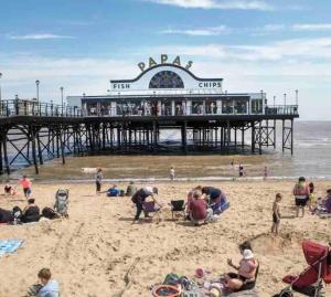 people on the beach in front of a pier at Boho Beach House: Hot Tub in Cleethorpes