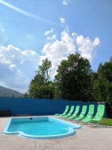 a swimming pool with chairs and a blue fence at Agroturystyka u Chlebków in Ochotnica Górna