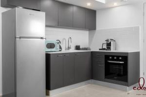 a kitchen with black and white cabinets and a refrigerator at דירה במתחם עם בריכה 100 מטר מהים - By Edom in Eilat