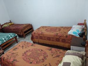 um quarto com três camas e dois repousa-pés em Hostal El Farolito em Humahuaca