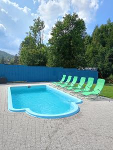 a swimming pool with chairs and a blue fence at Agroturystyka u Chlebków in Ochotnica Górna