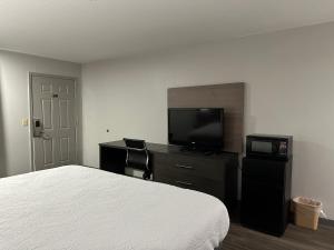 a bedroom with a bed and a flat screen tv at Budget Inn Muskogee in Muskogee