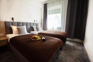 ドンブロヴァ・グルニチャにあるHotel Pogoria Residenceのベッド2台、フルーツのボウルが付いたホテルルームです。