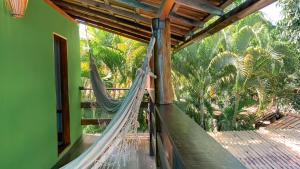 a hammock on the porch of a house with palm trees at Pousada Lumar in Caraíva