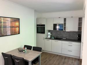 a kitchen with white cabinets and a table and chairs at Havelstern Ketzin, Ferienhaus Zander in Ketzin