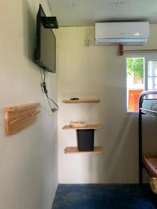 a room with a tv and shelves on the wall at Hostal Aguas Verdes in Santa Catalina