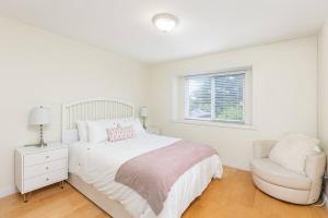 um quarto branco com uma cama e uma cadeira em Home near Downtown Vancouver East@ Joyce Skytrain em Vancouver