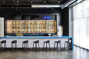 a bar with stools in a room with alcohol bottles at Aloft San Francisco Airport in Millbrae