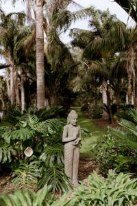 a statue of a person standing in a garden at The Villa at Bali Garden Matakana in Omaha