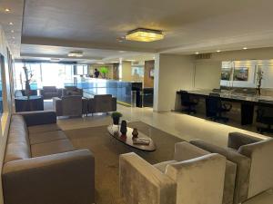 a living room with couches and a bar in the background at Flat beira-mar Marinas in João Pessoa
