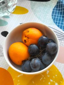 una ciotola di arance e uva su un tavolo di Chambre d hôte a Falaise