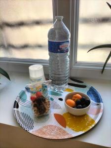 un piatto con una bottiglia d'acqua e un cesto di frutta di Chambre d hôte a Falaise
