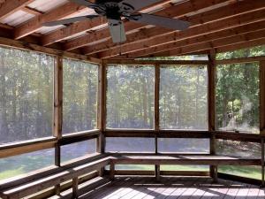 a screened in porch with a ceiling fan and windows at Redbud Cottage in Maumee