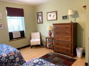 a bedroom with a bed and a dresser and a window at Redbud Cottage in Maumee +6 photos