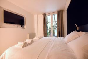 Cosy flat - Saint germain في باريس: غرفة نوم بسرير ابيض عليها مناشف