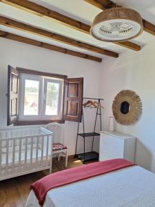 sypialnia z białym łóżeczkiem dziecięcym i oknem w obiekcie Casa da Ribeira w mieście Alcanede