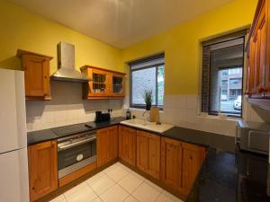 a kitchen with yellow walls and wooden cabinets and a sink at Elegant Weybridge Apartment near Train Station in Oatlands Park