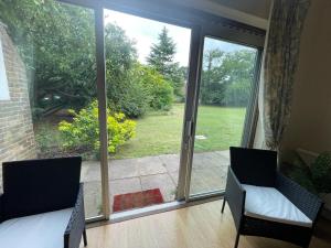 a room with two chairs and a large glass window at Elegant Weybridge Apartment near Train Station in Oatlands Park