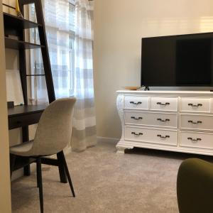 een woonkamer met een televisie en een dressoir met een stoel bij Mansfield St in Fredericksburg