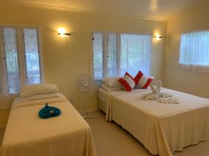 1 Schlafzimmer mit 2 Betten, einem Ventilator und Fenstern in der Unterkunft Tia Maria Retreat in Rarotonga