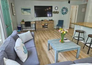 ein Wohnzimmer mit einem Sofa und einem Tisch mit Blumen in der Unterkunft Luna Azul, cozy condo only steps to Mission Beach! Free Internet in San Diego