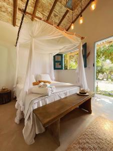 um quarto com uma cama de dossel e um banco de madeira em Pousada Céu de Corumbau em Corumbau