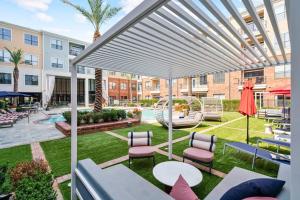 a patio with chairs and tables and a white pergola at Perfect Location/ Resort Style Pool/Fast Wi-Fi in Houston