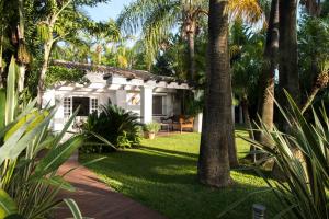 Villa in a palm tree plantation في مربلة: منزل أبيض مع أشجار النخيل في الفناء