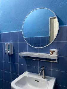 La salle de bains est pourvue de carrelage bleu, d'un lavabo et d'un miroir. dans l'établissement RumahRehat, à Kampong Molek
